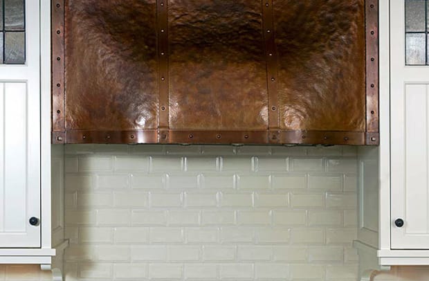 The copper stove hood was designed by architect Greg Klein and fabricated by Archive Designs. Cabinet doors have leaded-glass accents.