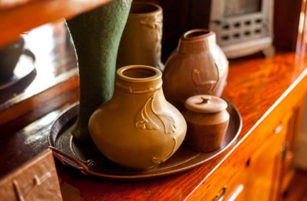 The couple’s collection of sought-after LoneSomeVille Pottery includes blue-green bowls and an assortment of vases; the lidded jar is wood, from Belize.