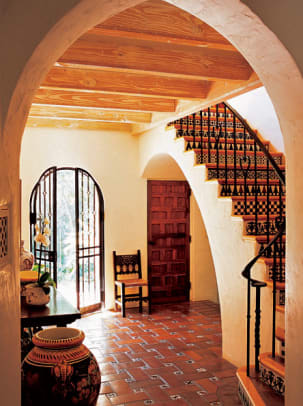 Clay tiles in a lattice-weave patern with hand-decorated accent tiles ground a Spanish Colonial Revival house.