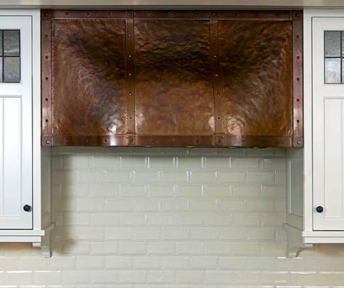 The copper stove hood was designed by architect Greg Klein and fabricated by Archive Designs. Cabinet doors have leaded-glass accents.