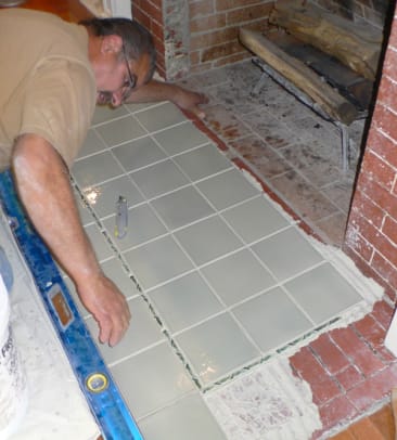 Bill uses a level and his eyes to make sure tiles line up before the mortar is fully set.