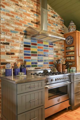 Reclaimed garden bricks were used on one wall of the kitchen (originally an attached garage). Colorful paint creates a focal point behind the stove.