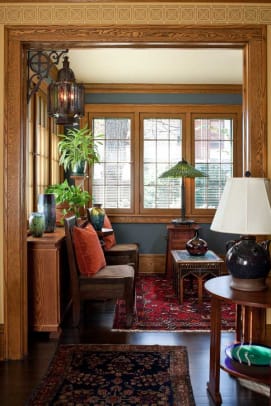 Navy-blue walls work in the bright sunroom; the table lamp by the window is by Century Studios.