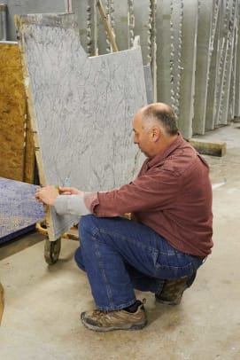 Longtime employee Doug Teter marks a slab to be cut. It’s similar to laying out a dress pattern on fabric, he says: “every day it’s a different puzzle.”