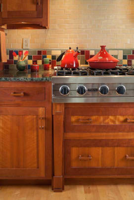 A tired, remodeled kitchen was gutted and rebuilt with cherry cabinets and stained-glass transoms by local artisans.