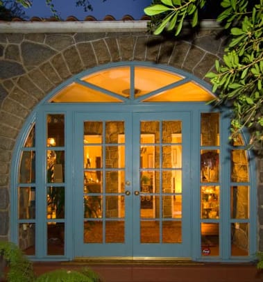 A view to the open interior is through French doors set in a stone arch.
