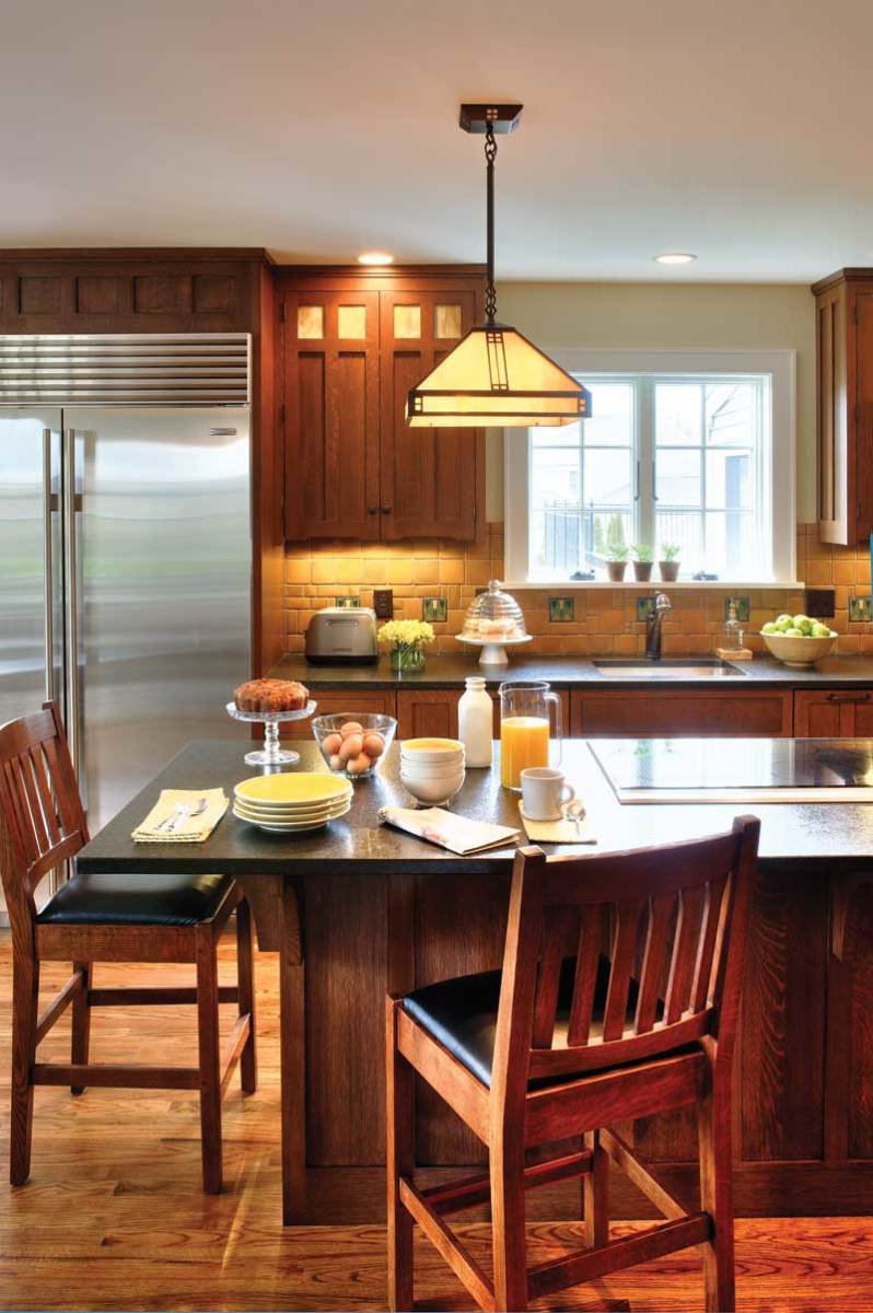 Stainless steel appliances are built into cabinet runs. The island is treated as a furniture piece, its cooktop barely noticeable when not in use.
