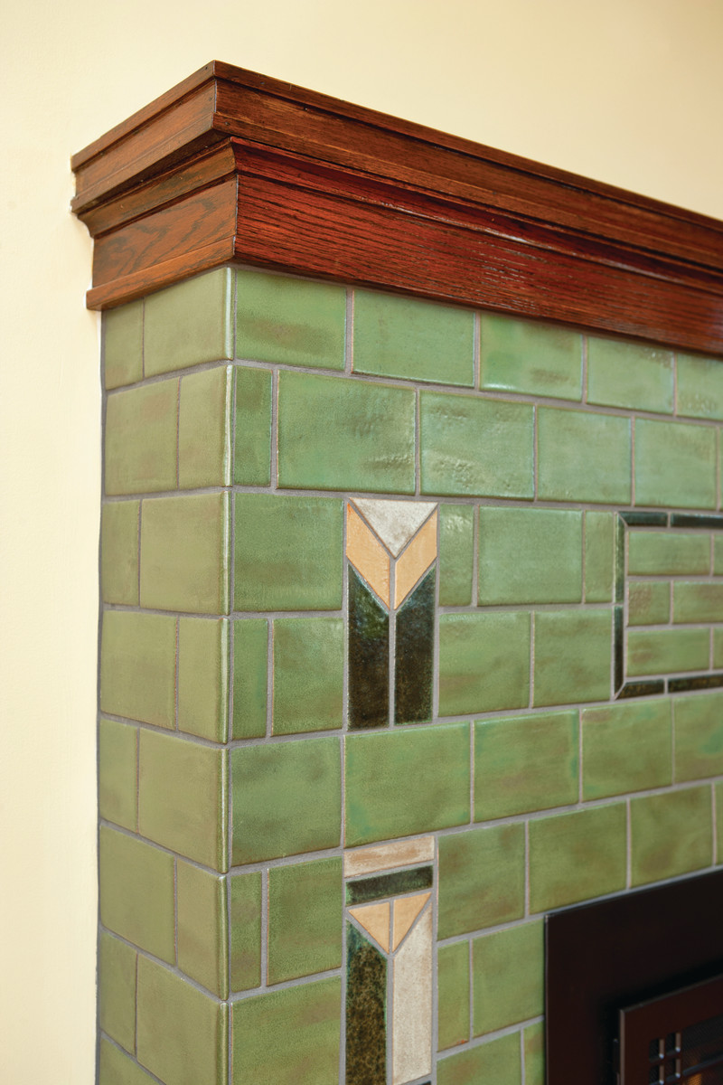 Field tiles in Pesto green on a fireplace are accented with geometric tiles in a Prairie School design.