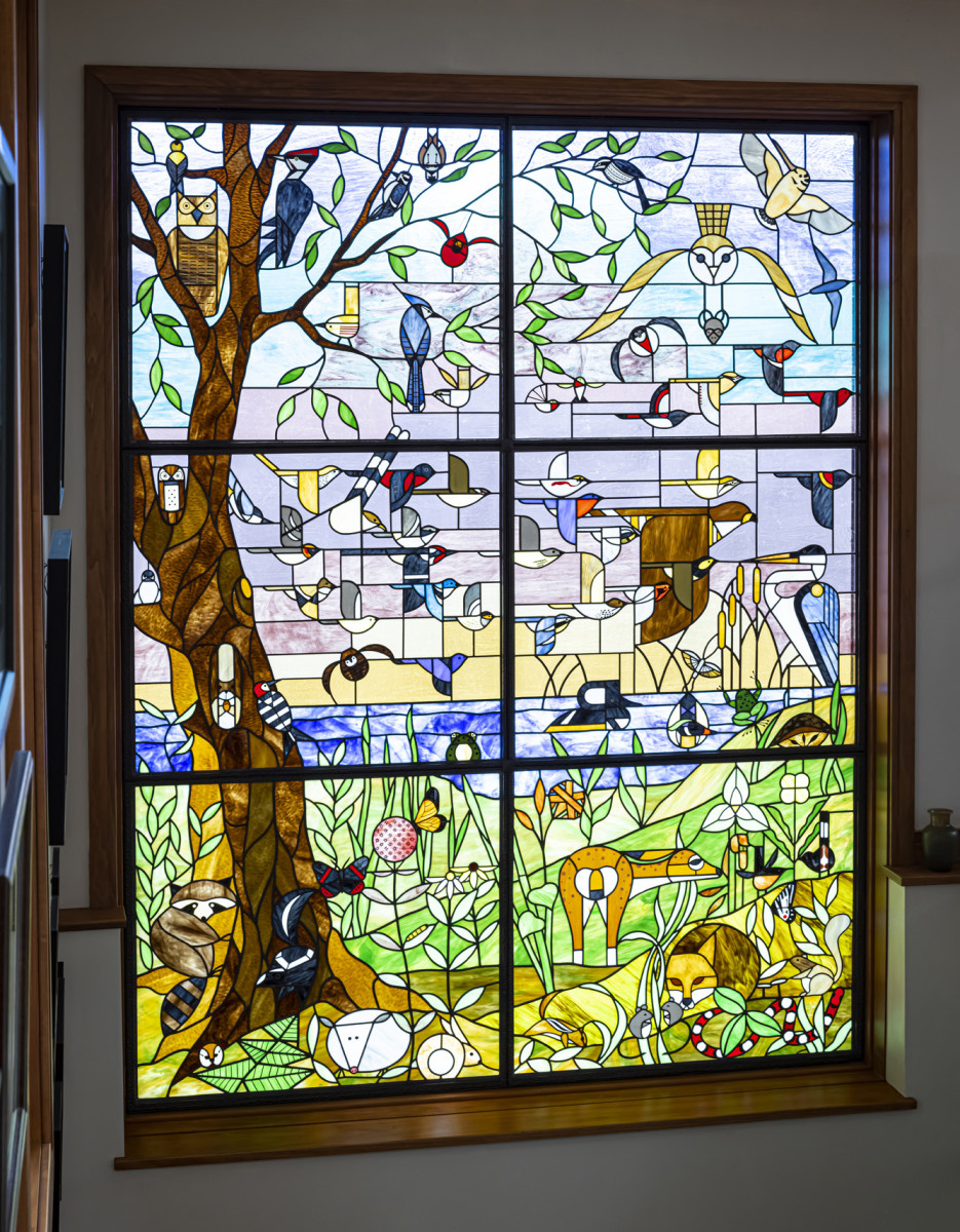 An art window nearly nine feet tall shows 50 species of birds, 13 animals, 4 kinds of insects, and native plants from the property. It took glass artist Susan McCracken a year to complete.
