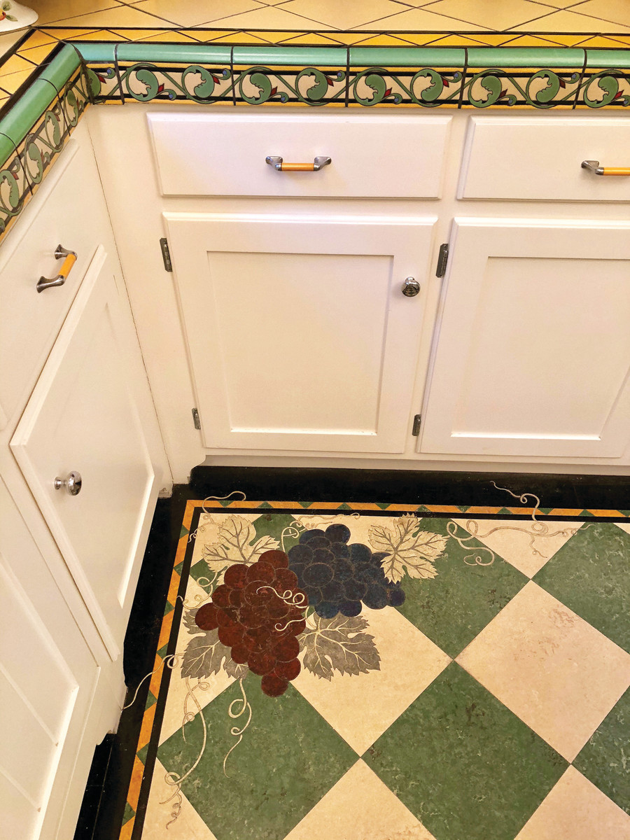 A grape motif is inlaid into a checkerboard floor. “The botanicals are the most difficult I cut; I say I’ll never do it again!”