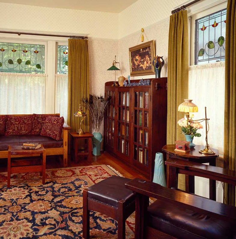 the-living-room-has-a-neutral-palette-with-morris-pattern-wallpapers-in-ivory-and-beige-stickley-antiques-include-the-triple-door-bookcase-and-the-paddle-arm-morris-chair.jpg